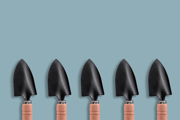 A composition of small garden blades arranged in a row at the bottom on a green-blue background. The place to copy. Concept: poster for the design of advertising media for the garden.