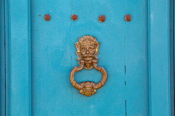 Historic metal door knocker on a turquoise door in, Barichara, Colombia
