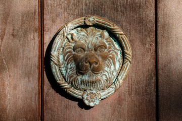 Historic round metal door knocker with lion's head in warm light, Barichara, Colombia