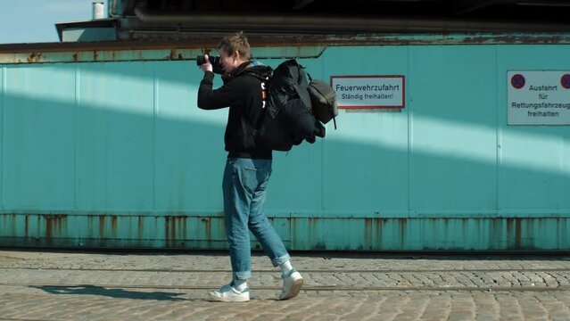 Young male photographer with backpack stops to take a picture of something. Slow Motion 4K