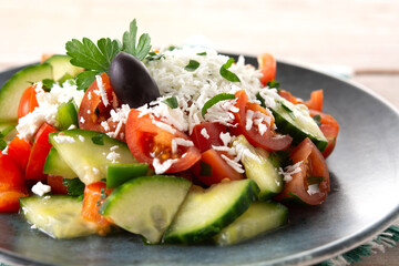 Traditional Bulgarian shopska salad with tomato,cucumber and bulgarian sirene cheese on wooden table