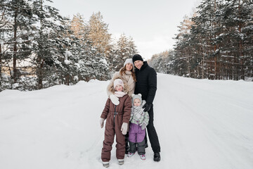 Fototapeta na wymiar dad and mom and two daughters walk through the snowy forest