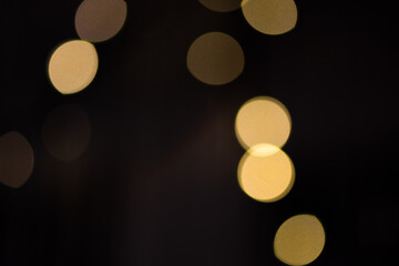 Golden abstract bokeh lights over black background. Holiday background for design.