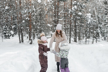 Fototapeta na wymiar mother with two daughters walks in a snowy forest on her day off