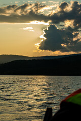 sunset on the background of mountains and rivers the rays of the sun break through the beautiful clouds