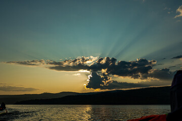 sunset on the background of mountains the rays of the sun break through the beautiful clouds