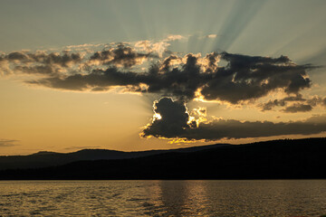 sunset on the background of mountains the rays of the sun break through the beautiful clouds
