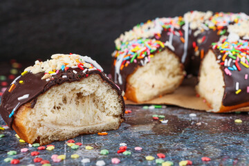 Chocolate donut decorated with colored sprinkles and chopped almonds.