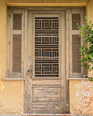 old weathered olive green painted door and double linear window shutters