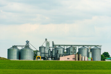 A large modern plant for the storage and processing of grain crops. view of the granary on a sunny day against the blue sky. End of harvest season. silver silos on agro manufacturing plant