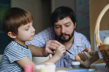 father and kid painting eggs for easter