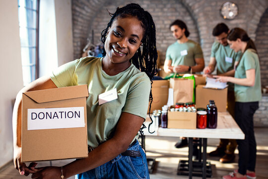 Portrait of female African American volunteer holding a box with donation.