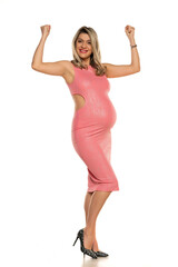 Pregnant woman in tight pink dress showing biceps in studio