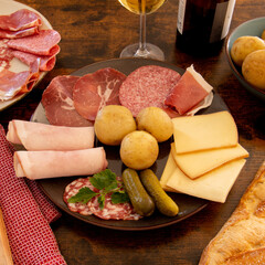 charcuterie plate with potatoes and wine on wooden table