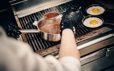 chef cooking meat sauce in pan on grill in kitchen
