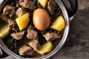 Traditional Jewish cholent in casserole on wooden table. Close up	