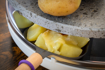 cheese melting in a raclette machine with potatoes close-up