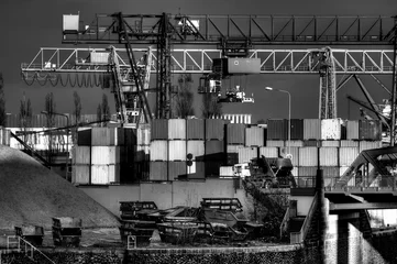 Deurstickers Ein Containerhafen für Binnenschiffe mit Containern, Müllbehältern und Verladekränen in Schwarz-weis © Frank Wagner