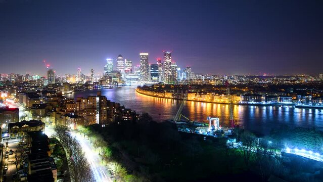 London skyline timelapse at night over a busy road and next to River Thames with modern skyscrapers above horizon