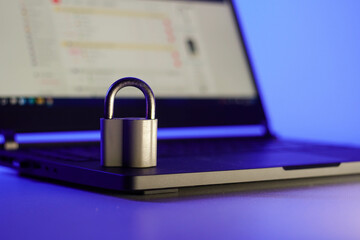 Locked metal padlock on a laptop keyboard over blue background. Cyber security, antivirus software concept.