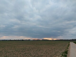 Sonnenuntergang, gefolgt von bunten Wolken. Der Himmel über den schlafenden Feldern und Bäumen. Die Natur malt den Himmel und löscht ihn aus. Romantische Szenen für Hintergründe. Dämmerung in Rottönen