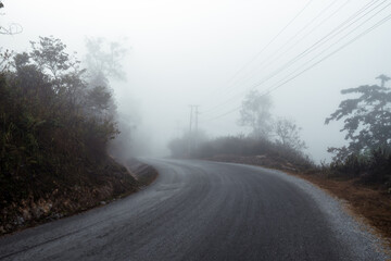 Asphalt road in a fog in the mountains
