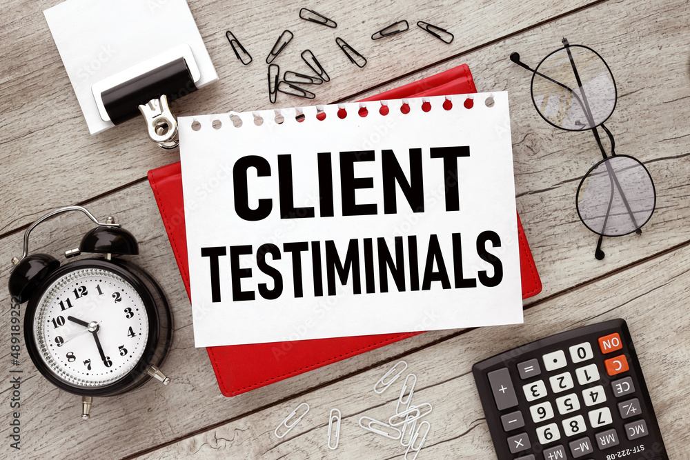 Poster client testimonials. a red notepad with a white sheet of paper with text, on the table, next to a pe