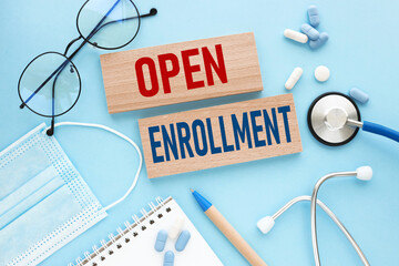 OPEN ENROLLMENT . text on wooden blocks on a blue background. stethoscope pills medical mask....