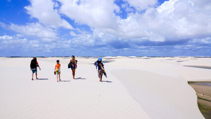 A group of people is walking in the national park Lencois Maranhenses in Brazil