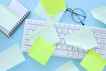 many ideas. busy work schedule. Flat lay of the workplace. white keyboard. a lot of sticky note paper on a computer keyboard with a blue paper clip background. office equipment.