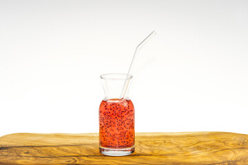Watermelon juice with basil seeds in glass cup with straw on wooden table and white background