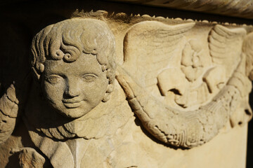 Ein lächelnder Engel Kopf an der Ecke eines Grabsteins aus der Biedermeier Zeit. Der Stein steht...