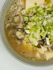 A bowl of shallot, tofu and mushroom soup