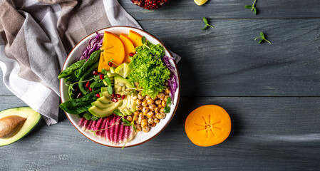 Fresh salad with roasted chickpeas, avocado, persimmon, spinach, avocado, watermelon radish and seeds. banner, catering menu recipe place for text, top view
