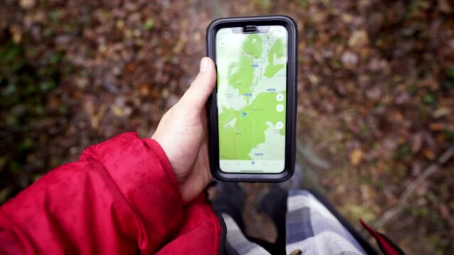 trekking adventurer solo traveller lost in the woodland forest trail, looking for internet fast data 5g signal for navigate the maps of a remote area on new modern smartphone device