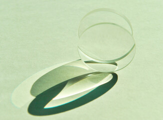 Close up of sunlight through clear circular convex and concave lens with different focus lengths overlapping. Mixture refection and refraction of light create artistic shade and shadow on white paper