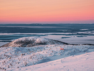 Beautiful Arctic sunset. Scenic colorful sky at dawn. Winter time. Cabin in winter. Dubldom on the mountain Volodyanaya Kandalaksha, Murmansk region in Russia.
