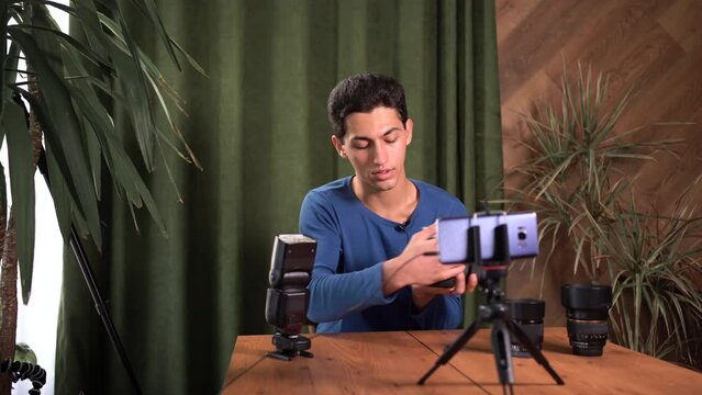 training for beginner photographers, online courses. A Muslim man records a video review of photographic equipment using an application on a smartphone. The structure of the camera and lens.