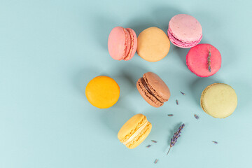 Cake macaron or macaroon on turquoise background from above, colorful almond cookies, pastel colors, vintage card, top view