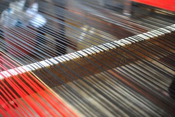 Closeup image of fine Thai silk yarn textile hand loomed in wooden weaving machine. Asian traditional cultural handmade silk.
