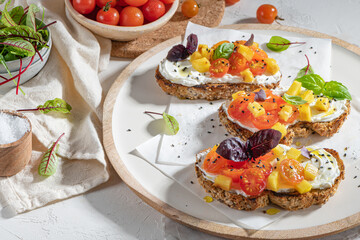 Italian bruschettas with roasted tomatoes, cream cheese, pineapple slices and herbs on a kitchen countertop. Prepared to serve