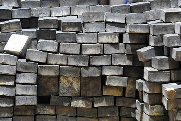 Direct view of stack of grey cobble stones in square cube, arranged in order at site construction