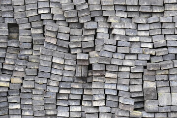 Direct view of stack of grey cobble stones in square cube, arranged in order at site construction