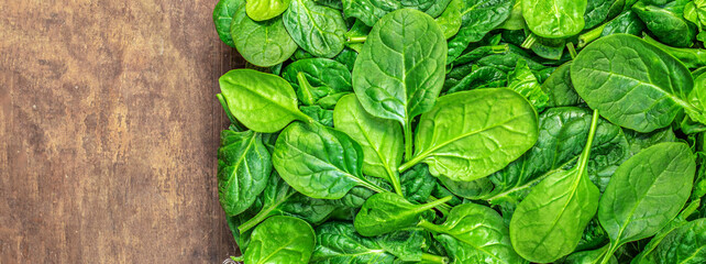 Spinach Wallpaper. Fresh Spinach baby leaves as a  background on a wooden table. Copyspace. Pattern. Top view.