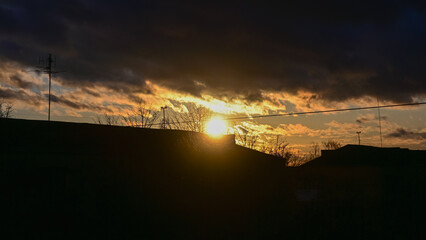 sunset in the city. cloudy sky. thick black clouds. the sun shines over the building. the sun is setting.