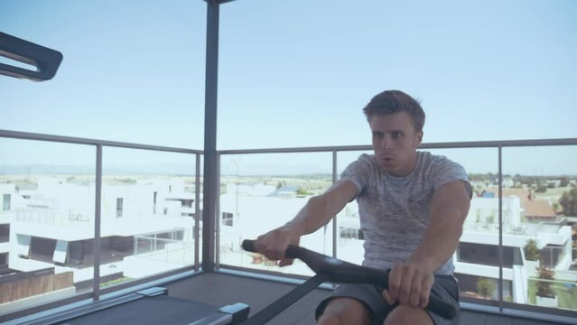 Man exercising with a rowing machine on a rooftop