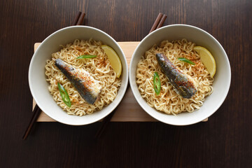 Instant noodles with sardine, chillies and seasonings in ceramic bowls.  Flat lay top view photo.  Food from above.