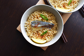 Instant noodles with sardine, chillies and seasonings in a ceramic bowl.  Flat lay top view photo.  Food from above.