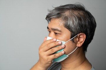 Sick Asian man wearing a medical face mask and Coughing and covering his mouth with my hand. Concept of protection pandemic coronavirus and respiratory disease