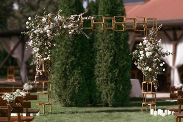 Wedding. Wedding ceremony. Arch. Arch, decorated with white flowers standing in the woods, in the wedding ceremony area.